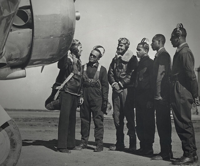 Five men listening to an instruction in front of an airplane.