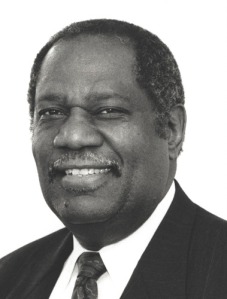 Black and white portrait of Robert Stanton wearing a suit and tie.